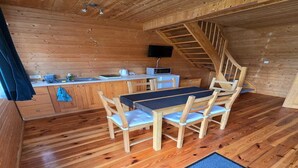 A wooden interior with a dining table, chairs, a kitchen area, and a staircase. - Terraced Home in Sarbinowo Near the Beach (Mielno)