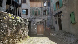 Un stretto vicolo acciottolato con muri in pietra e balconi in legno.