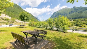 Un tavolo da picnic con panche in una zona erbosa, con una montagna sullo sfondo.