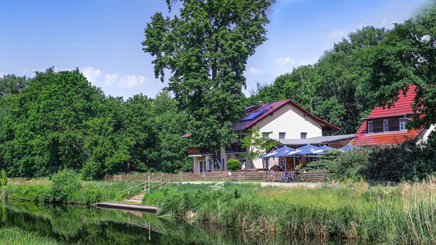 Un hotel sul lago con una terrazza in legno, un piccolo molo e un edificio con il tetto rosso.