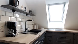 Una cucina con finestra, una macchina da caffè e un lavandino.