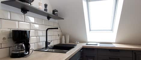 Een keuken met een raam, koffiezetapparaat en spoelbak.