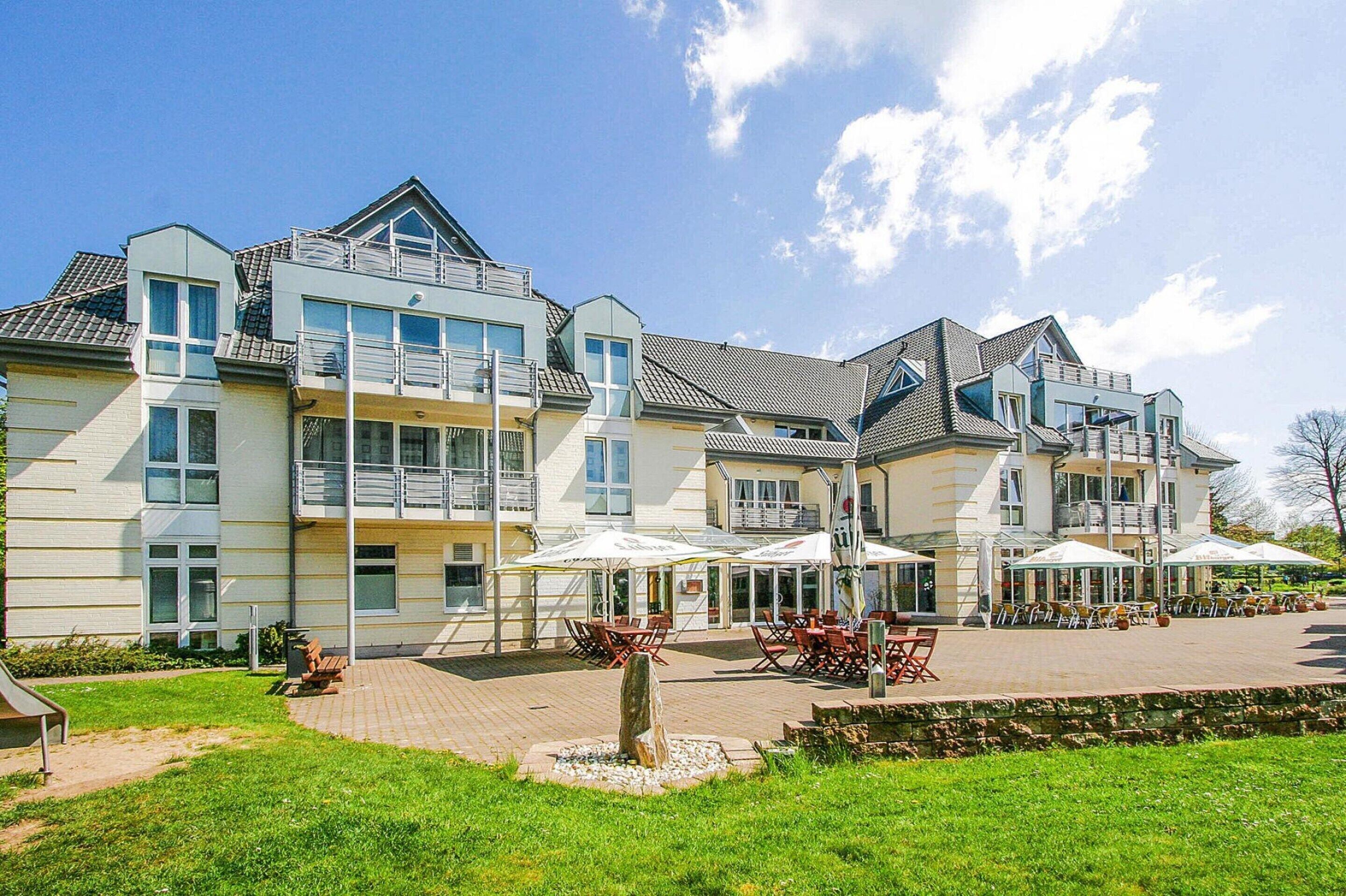 A multi-story hotel with outdoor seating and a landscaped garden.