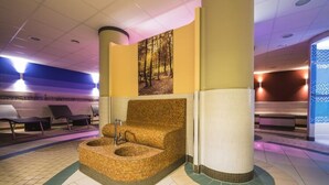 A spa area with a large, woven, circular seating area, a wall-mounted picture of a forest, and a tiled floor with a green and beige pattern. - Residenz Seestern, Boltenhagen (Boltenhagen)