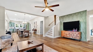 A spacious living area with a wooden coffee table, a sofa, and a TV on a wooden cabinet. - Modern Remodeled Farmhouse - Great Location (Piedmont)