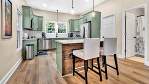 A modern kitchen with green cabinets, a wooden island, and pendant lighting. - Modern Remodeled Farmhouse - Great Location (Piedmont)
