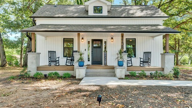 A two-story house with a front porch, a welcoming sign, and potted plants. - Modern Remodeled Farmhouse - Great Location (Piedmont)