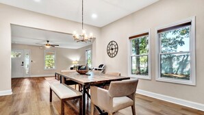 A spacious dining area with a wooden table, cushioned benches, and a chandelier. - Modern Remodeled Farmhouse - Great Location (Piedmont)