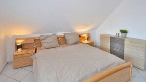 Een slaapkamer met een bed, nachtkastjes, een kaptafel en een bijzetmeubel.