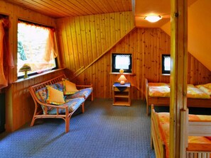 A cozy room with wooden walls, a sofa, a bed, and a television. - Comfortable Holiday Home With a Large Garden (Kołobrzeg)