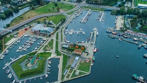 Luchtbeeld van een jachthaven met meerdere steigers en boten, verbonden door looppaden en wegen.