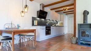 Una cocina moderna con comedor, que incluye una mesa de madera, sillas y una estufa empotrada.