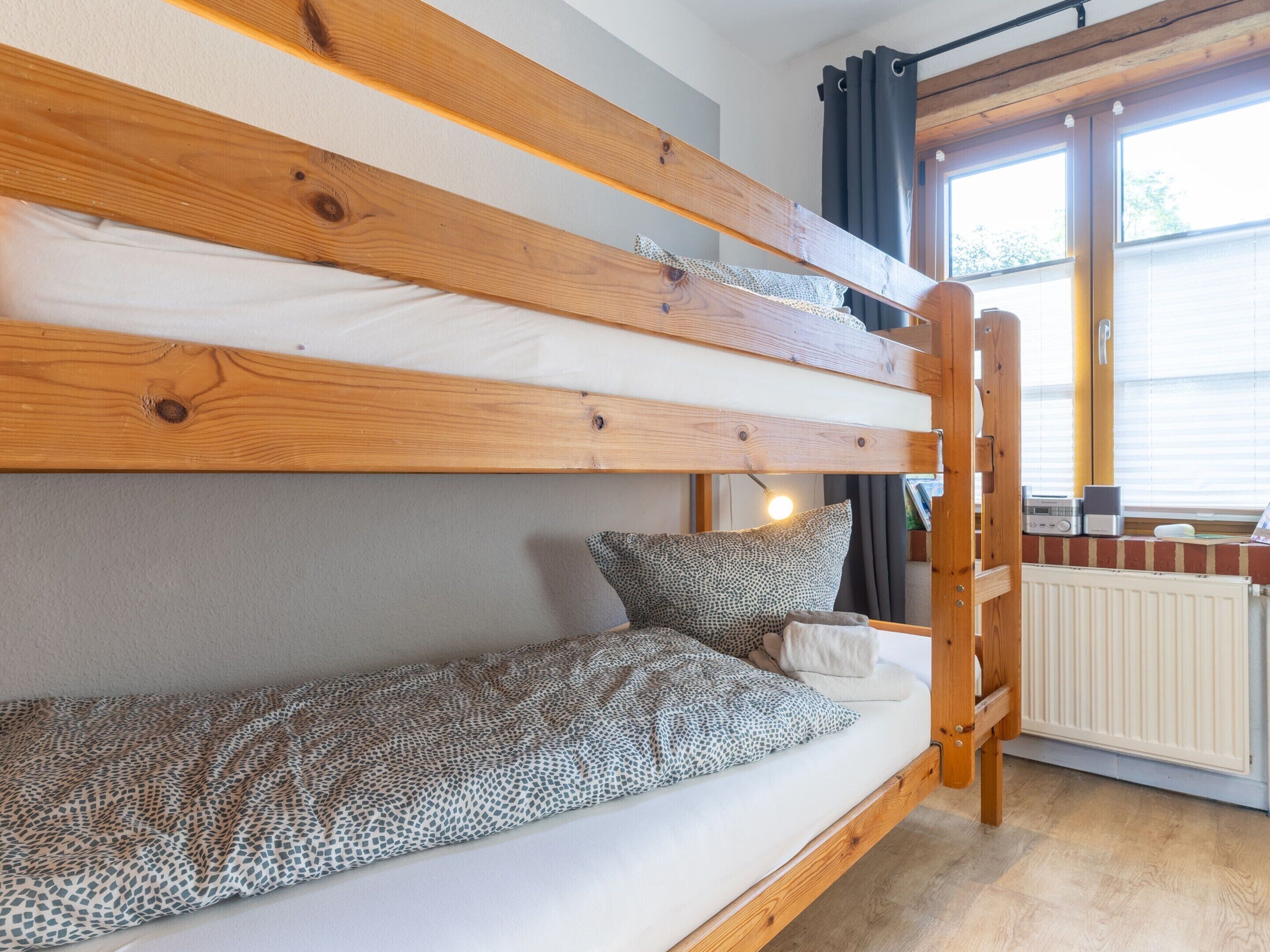 Un lit superposé avec une structure en bois, un matelas et un oreiller.