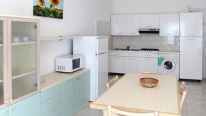 A compact kitchen with white cabinets, a microwave, a stove, and a washing machine. - Residence Ambassador, Lido del Sole (San Michele al Tagliamento)