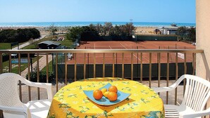 A balcony with a table set for two, overlooking a tennis court and beach. - Residence Ambassador, Lido del Sole (San Michele al Tagliamento)