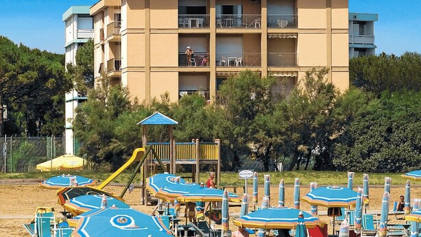 A beachfront hotel with multiple balconies, beach umbrellas, and a playground. - Residence Ambassador, Lido del Sole (San Michele al Tagliamento)