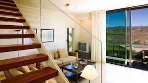 A modern living room with a glass staircase, a sofa, a coffee table, and a television. - Holiday Home, Maspalomas (San Bartolomé de Tirajana)