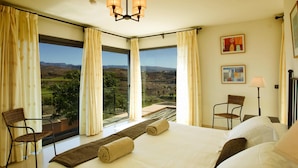 A hotel room with a large bed, two chairs, a view of a landscape, and a chandelier. - Holiday Home, Maspalomas (San Bartolomé de Tirajana)