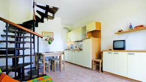 Un espace de vie compact comprenant un escalier, un coin repas, une cuisine et un téléviseur.