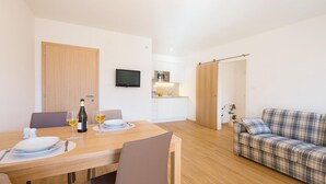 A modern living room with a dining area, a sofa, and a kitchen in the background. - Apartment in Dorf Tirol Near Spronser Lakes (Tirolo)