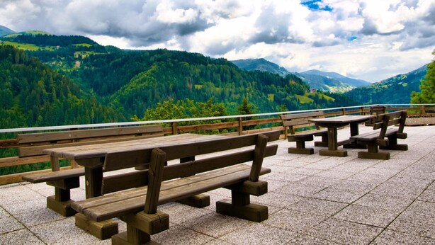 A series of wooden picnic tables on a paved terrace with a scenic mountain backdrop. - Farmhouse in Afritz Near Gerlitzen Ski Center (Treffen)