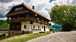A two-story wooden house with balconies, a gravel driveway, and a tree in the foreground. - Farmhouse in Afritz Near Gerlitzen Ski Center (Treffen)