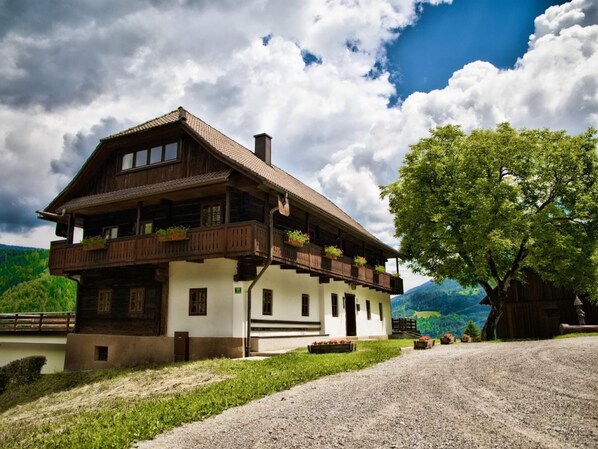 A two-story wooden house with balconies, a gravel driveway, and a tree in the foreground. - Farmhouse in Afritz Near Gerlitzen Ski Center (Treffen)