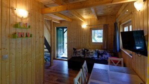 A wooden cabin interior with a sofa, dining table, and TV. - Cottage in Pobierowo for 5 People (Rewal)