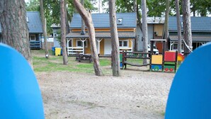 A playground area with sand, trees, and wooden structures. - Cottage in Pobierowo for 5 People (Rewal)