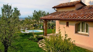 Ein Haus mit Ziegeldach, Schwimmbad und Garten.
