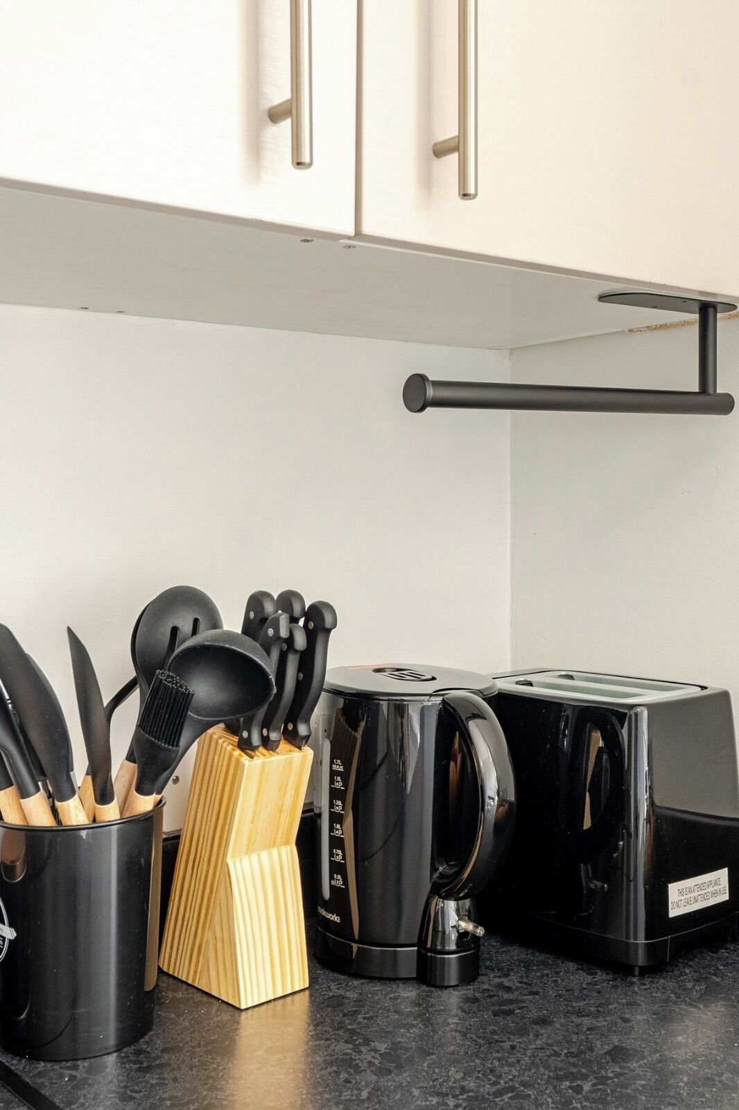 A kitchen with a toaster, a coffee maker, and a utensil holder on the counter.