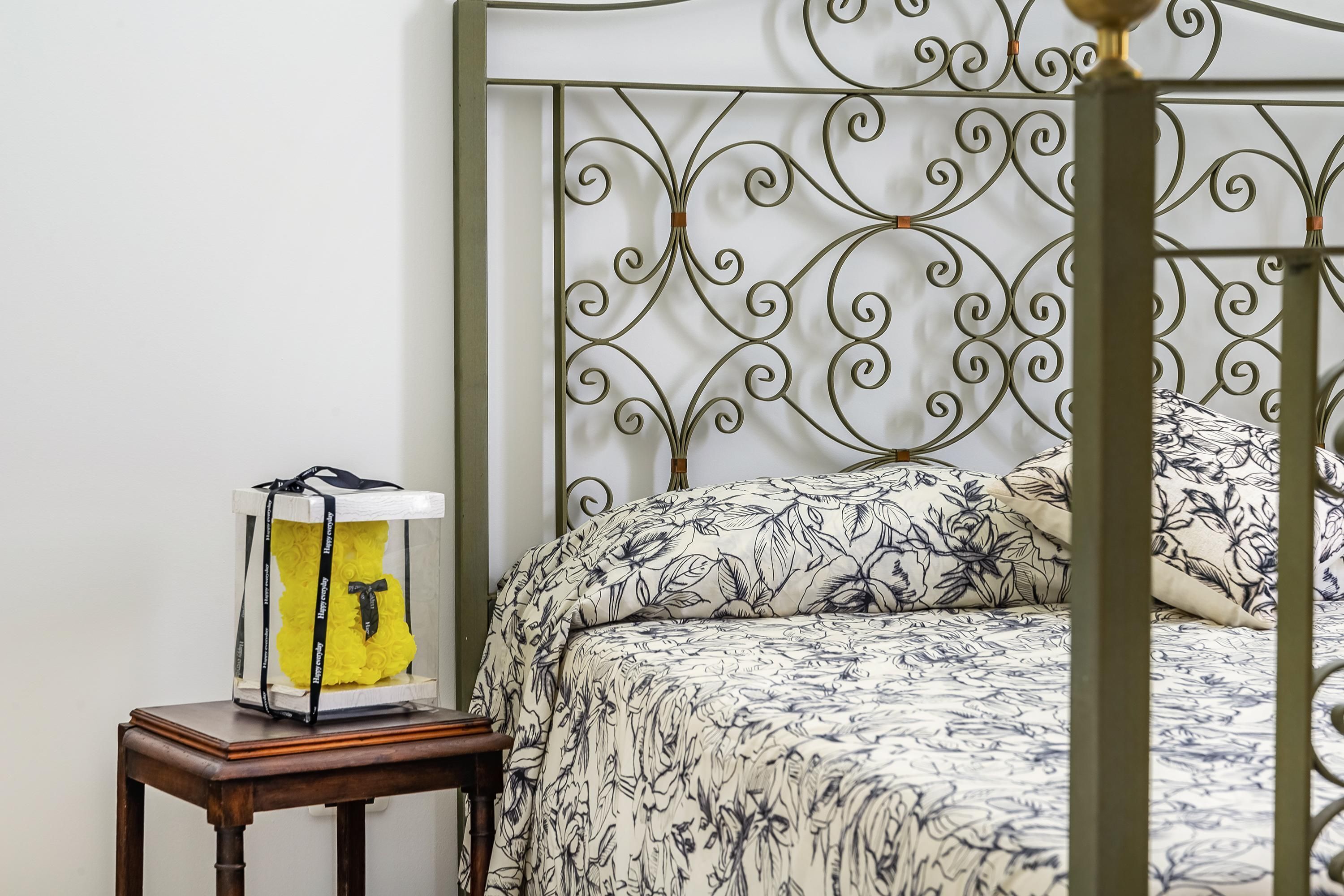 A bed with a floral-patterned bedspread and a metal headboard with a decorative design.
