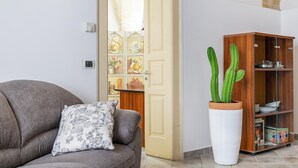A living room with a grey sofa, a white potted cactus, and a wooden cabinet with glass doors. - Terra Mia In The Historic Center Of Lecce (Lecce)