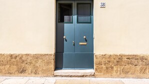 A dark blue door with a small window and a brass handle, set in a beige wall with a stone base. - Terra Mia In The Historic Center Of Lecce (Lecce)