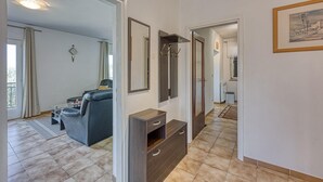 A hotel room with a sofa, a wooden cabinet, a mirror, and a framed picture on the wall. - Pool House Lilly in Vi Njan (Visnjan)