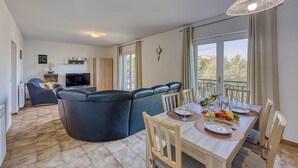 A modern living room with a sofa, dining table, and TV. - Pool House Lilly in Vi Njan (Visnjan)