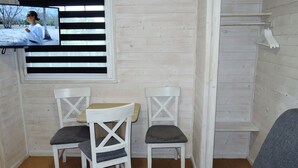 A cozy room with a TV mounted on the wall, two white chairs with grey cushions, a small table, and a grey sofa. - Dziwnowek Holiday House Near Beach (Kamien Pomorski)