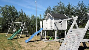 A playground with a slide, climbing wall, and a small house structure. - Dziwnowek Holiday House Near Beach (Kamien Pomorski)