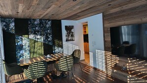 Et moderne interiør med træloft, et spiseområde med bord og stole samt udsigt til et køkken.