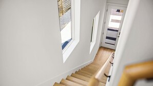 A wooden staircase with white walls and a view of the outside through a window. - Gorgeous New Build ~Luxury Finishes~ Huge Balcony (Austin)