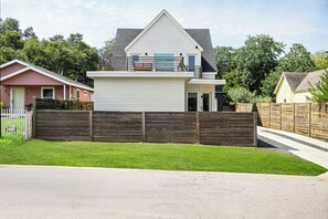Une maison à deux étages, avec une façade blanche, une clôture marron foncé et une pelouse bien entretenue.