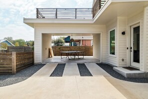 Un espace extérieur aménagé en terrasse, avec une table et des chaises, une clôture en bois et une vue sur les maisons voisines.