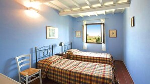 A bedroom with two beds, a chair, and a window with a view.