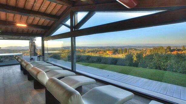 A modern outdoor seating area with a view of a landscaped garden and distant hills.