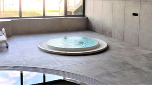 Une piscine intérieure moderne, dotée de grandes baies vitrées offrant une vue sur un quartier résidentiel.