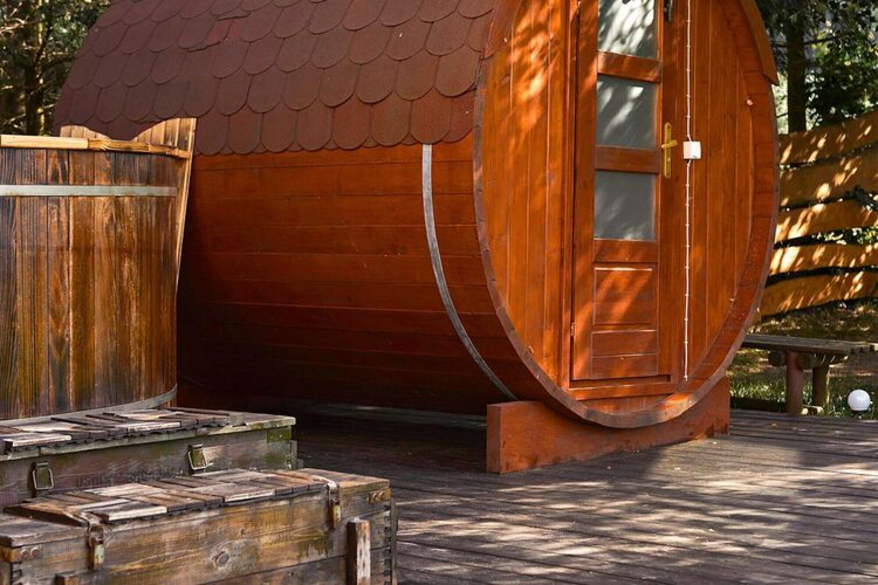 Un bâtiment en forme de tonneau, fait de bois, doté d’une porte et de fenêtres, et situé sur une terrasse en bois.
