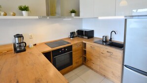 A compact kitchen with wooden countertops, a built-in oven, a microwave, a coffee maker, and a sink. - Cozy Cottage for 2 People Near the Sandy Beach (gmina Bedzino)