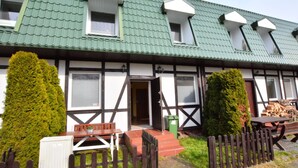 A traditional building with a green roof, multiple windows, and a wooden fence. - Cozy Cottage for 2 People Near the Sandy Beach (gmina Bedzino)