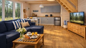 A cozy cabin interior with a sofa, breakfast table, kitchen, and a TV. - Holiday Home in Rewal Near Baltic Beach (Rewal)