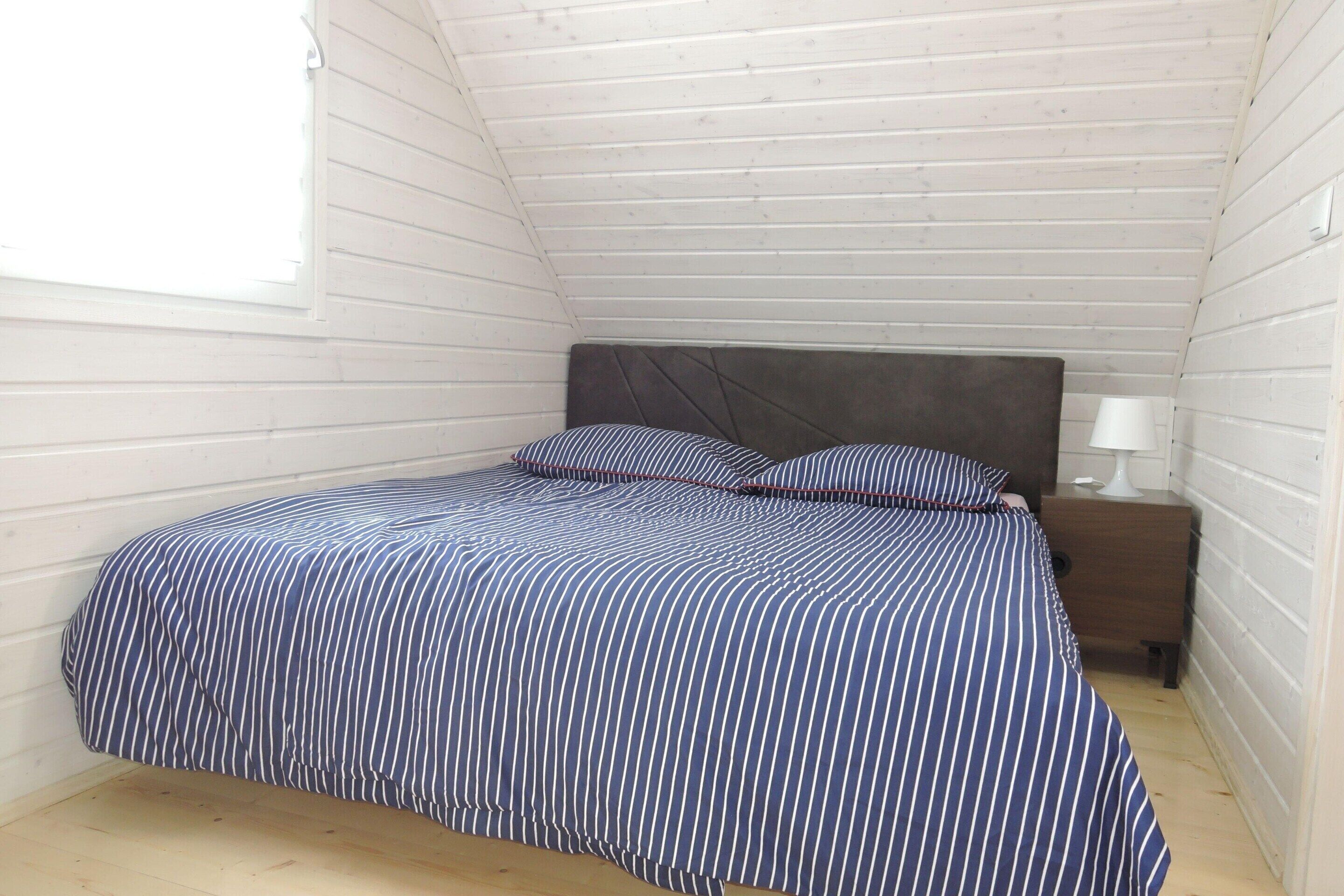 A small, single-bed room with a sloped ceiling and white walls.